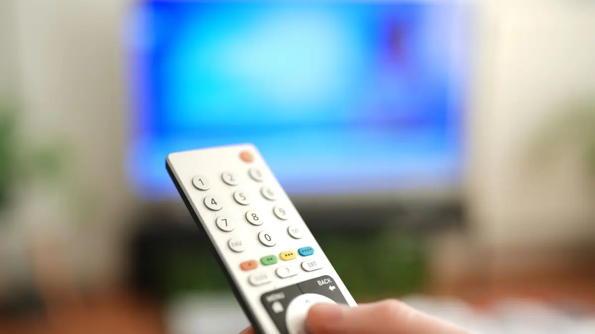 Ein Mann drückt einen Knopf auf einer TV-Fernbedienung: ILLUSTRATION - DVB-I soll auch mehr Komfort bringen - etwa eine Senderliste für alle linearen Fernsehprogramme, ganz gleich über welchen Empfangsweg. (zu dpa: «DVB-I: Neuer TV-Standard führt Empfangswege zusammen») Foto: Marcus Brandt/dpa/dpa-tmn - Honorarfrei nur für Bezieher des dpa-Themendienstes +++ dpa-Themendienst +++