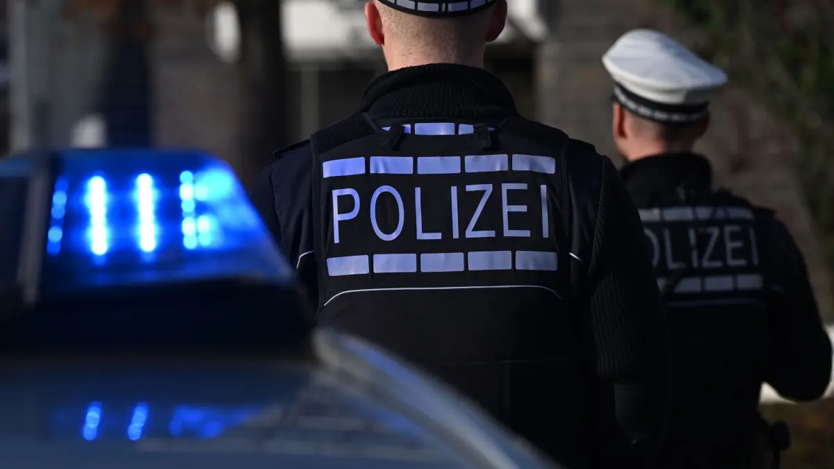 Polizei: ARCHIV - 03.12.2024, Baden-Württemberg, Stuttgart: Das Logo der Polizei auf der Dienstkleidung von Polizisten die vor einem Blaulicht stehen (gestellte Szene). (zu dpa: «Verdächtiger nach Angriff mit Holzstock in U-Haft») Foto: Bernd Weißbrod/dpa +++ dpa-Bildfunk +++