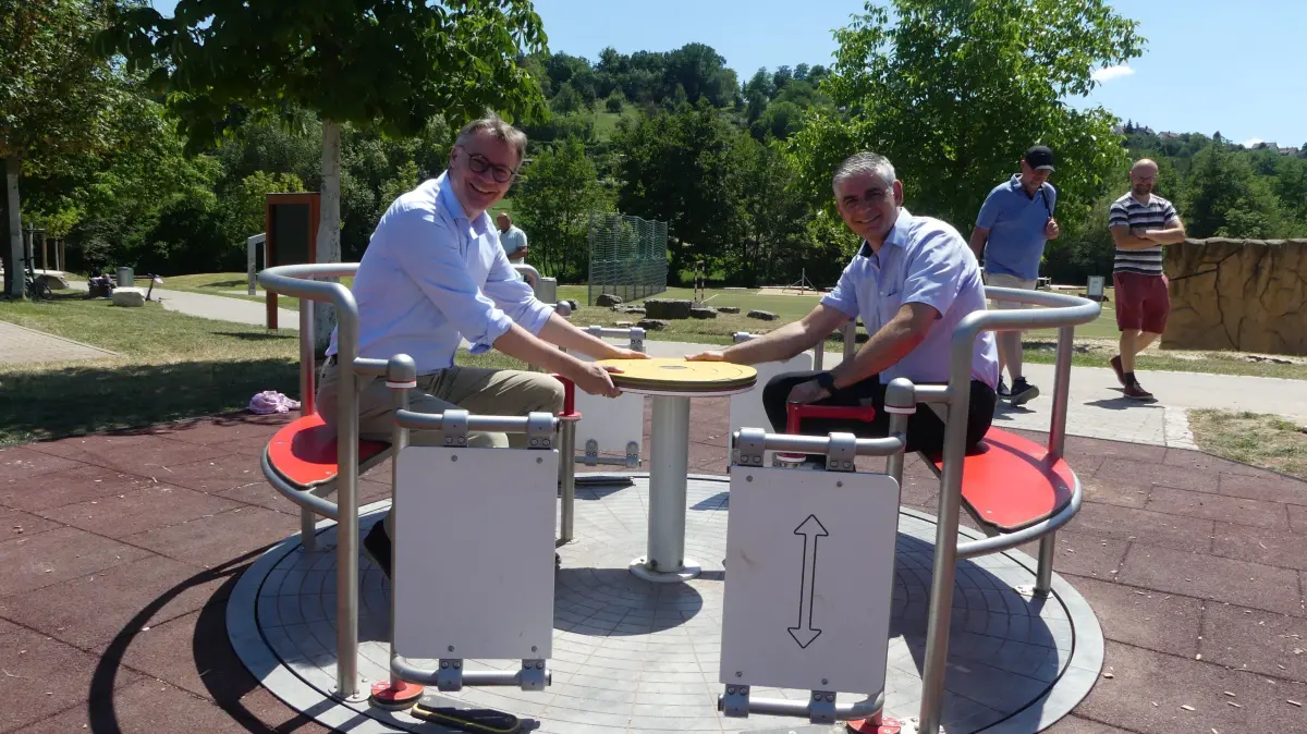 Bildunterschrift:Eines von drei inklusiven Spielgeräten von Regionaldirektor Alexander Lahl (links) und Bürgermeister Ioannis Delakos persönlich getestet.