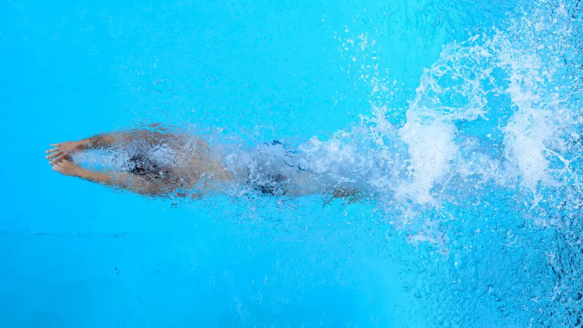Freibad: 18.06.2026, Brandenburg, Forst (Lausitz): Ein Schwimmer taucht nach dem Start oder einer Wende kraftvoll durch das hellblaue Wasser eines Schwimmbeckens. (zu dpa: «Freibad in Beelitz erweitert Öffnungszeiten wegen Hitze») Foto: Patrick Pleul/dpa +++ dpa-Bildfunk +++