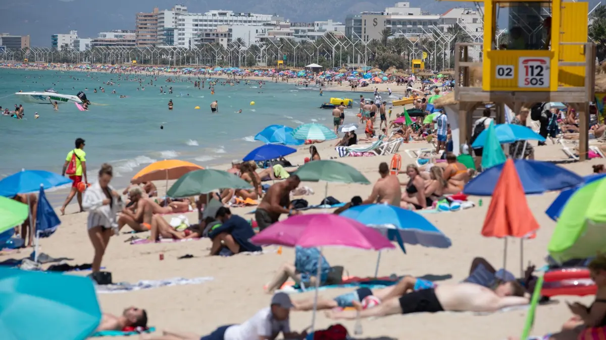 Sommer auf Mallorca: ARCHIV - 24.06.2026, Spanien, Palma: Menschen entspannen am Strand der Playa de Palma an einem warmen Sommertag. (zu dpa: «Bei früherem Abflug droht Ärger - Was zur Schulpflicht gilt») Foto: Clara Margais/dpa +++ dpa-Bildfunk +++