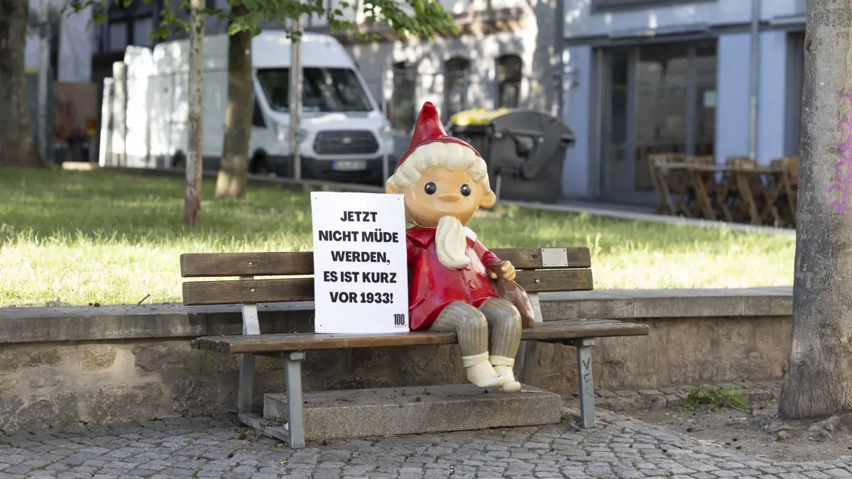 Das Sandmännchen aus DDR-Tagen sitzt mit einem Schild "Jetzt nicht müde werden. Es ist kurz vor 1933" auf einer Parkbank im sonnigen Erfurt. Vor dem Bundesparteitag der AfD haben Unbekannte die Kika-Figuren in der Innenstadt mit Demo-Schildern ausgestattet. Sie rufen zum Protest gegen die Veranstaltung auf.
