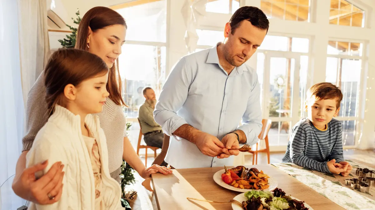 Junges Ehepaar mit Kindern bereitet ein festliches Mittagessen im Esszimmer zu Hause vor. Attraktiver Mann und seine Frau machen leckeren Salat aus frischem Gemüse. Glückliche Familie. Interieur mit Weihnachtsdekoration A young married couple with children are preparing a festive lunch in the dining room at home. An attractive man and his wife make a delicious salad of fresh vegetables. A happy family. ,model released, Symbolfoto Copyright: xZoonar.com/DashaxPetrenkox 22584667 ,model released, Symbolfoto ,property released