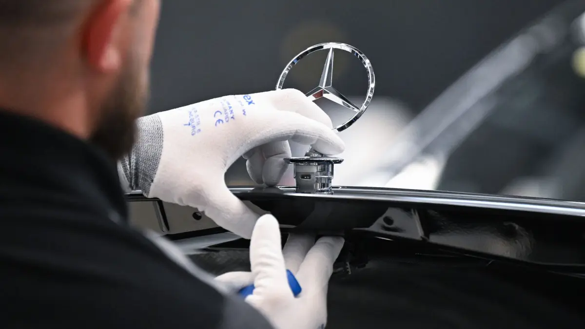 Mercedes-Benz: ARCHIV - 30.04.2026, Baden-Württemberg, Sindelfingen: Ein Mercedes-Benz Arbeiter montiert im Mercedes-Benz Werk Sindelfingen in der Factory 56 einen Mercedes Stern auf ein Fahrzeug der S-Klasse. (zu dpa: «Mercedes verkauft weniger - aber deutliches Plus bei E-Autos») Foto: Bernd Weißbrod/dpa +++ dpa-Bildfunk +++