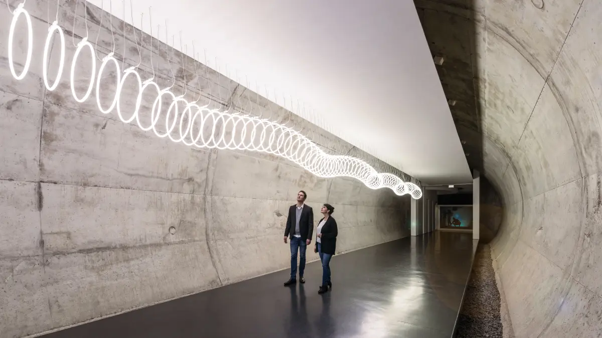 Eine beeindruckende Lichtinstallation von Barbara Trautmann führt entlang eines Tunnels hinzu dem Aufzugsturm, der in den Neubau führt.