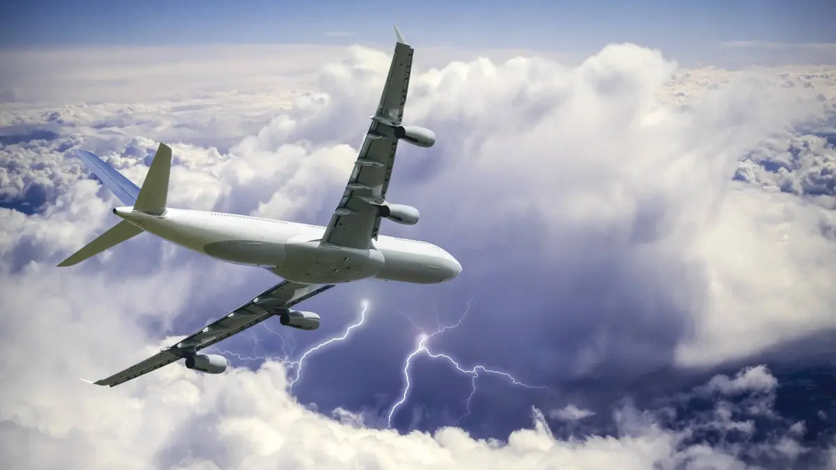 Ein Passagierflugzeug fliegt über einer Gewitterwolke.