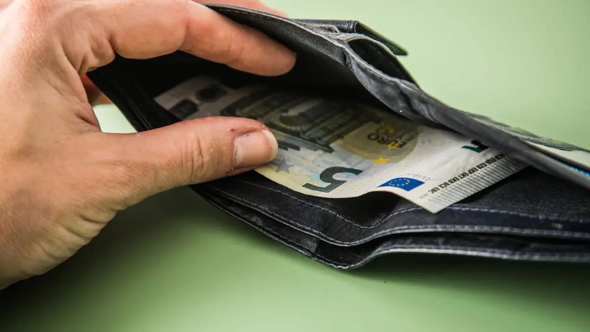 Portemonnaie aus Leder mit 5-Euro-Schein: ILLUSTRATION - Arbeitnehmer haben ein Recht auf pünktliche Zahlung des Gehalts. (zu dpa: «Was tun, wenn das Gehalt nicht kommt?») Foto: Christin Klose/dpa-mag - Honorarfrei nur für Bezieher des Dienstes dpa-Magazin +++ dpa-Magazin +++