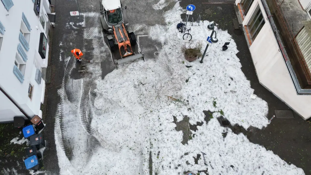 Unwetter in Baden-Württemberg - Hagel: 15.07.2026, Baden-Württemberg, Reutlingen: Mitarbeiter der Stadtreinigung entfernen Hagel, der nach einem Unwetter in der Innenstadt aufgetürmt wurde. (Luftaufnahme mit einer Drohne) Foto: Bernd Weißbrod/dpa +++ dpa-Bildfunk +++
