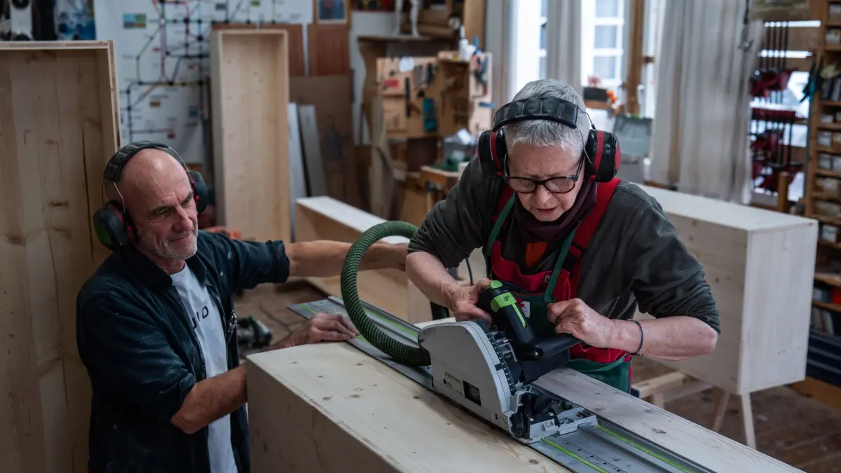 Angelika Paulus setzt die Tauchsäge an. Der Freiburger Schreinermeister und Workshopleiter Johannes Wittich behält die Sargbauerin im Blick.