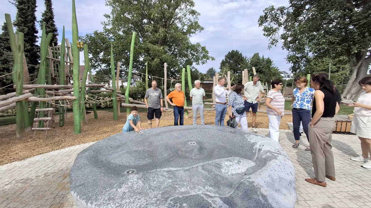 Stadträte bewundern den wasserspeienden Granitblock. Im Hintergrund ein Teil des Spielplatzes.