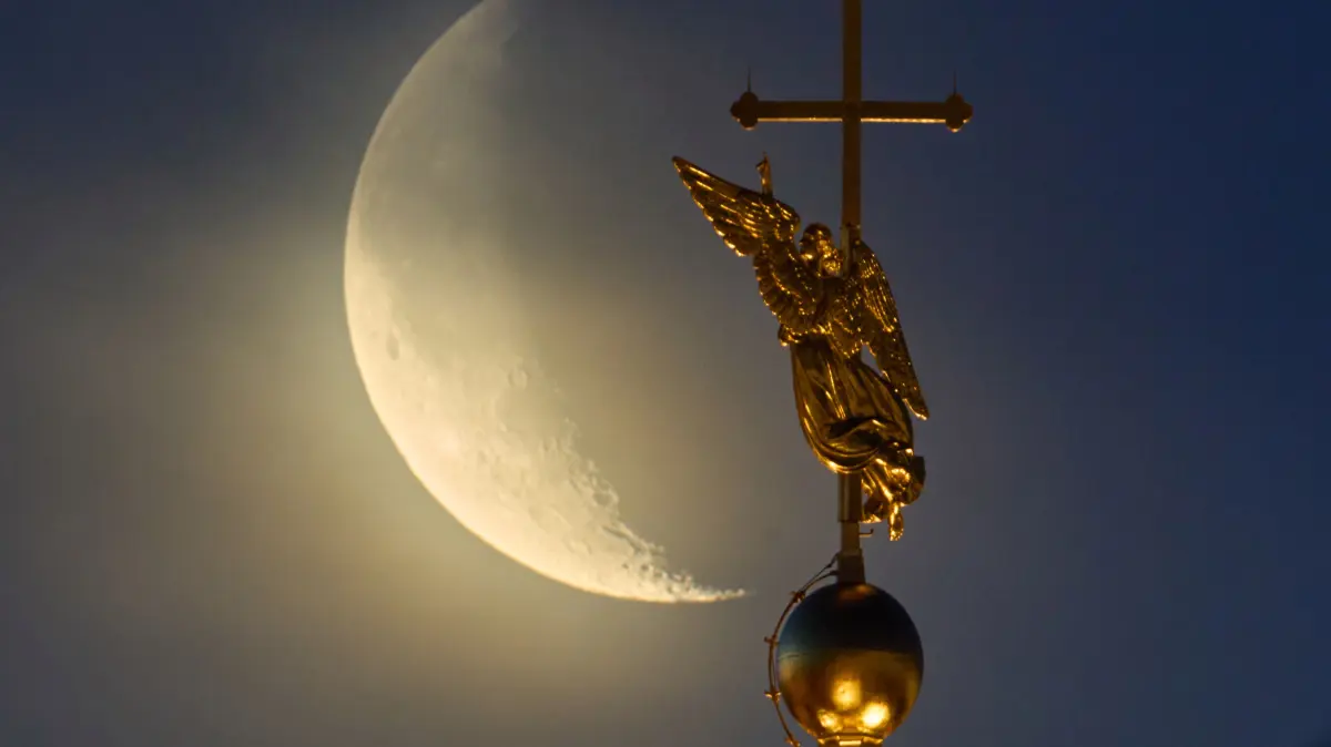 Der Mond geht hinter dem Wahrzeichen der russischen Stadt St. Petersburg – einer Wetterfahne in Form eines Engels, die auf der Spitze eines Turms der Peter-und-Paul-Kathedrale angebracht ist – aus den Wolken auf.