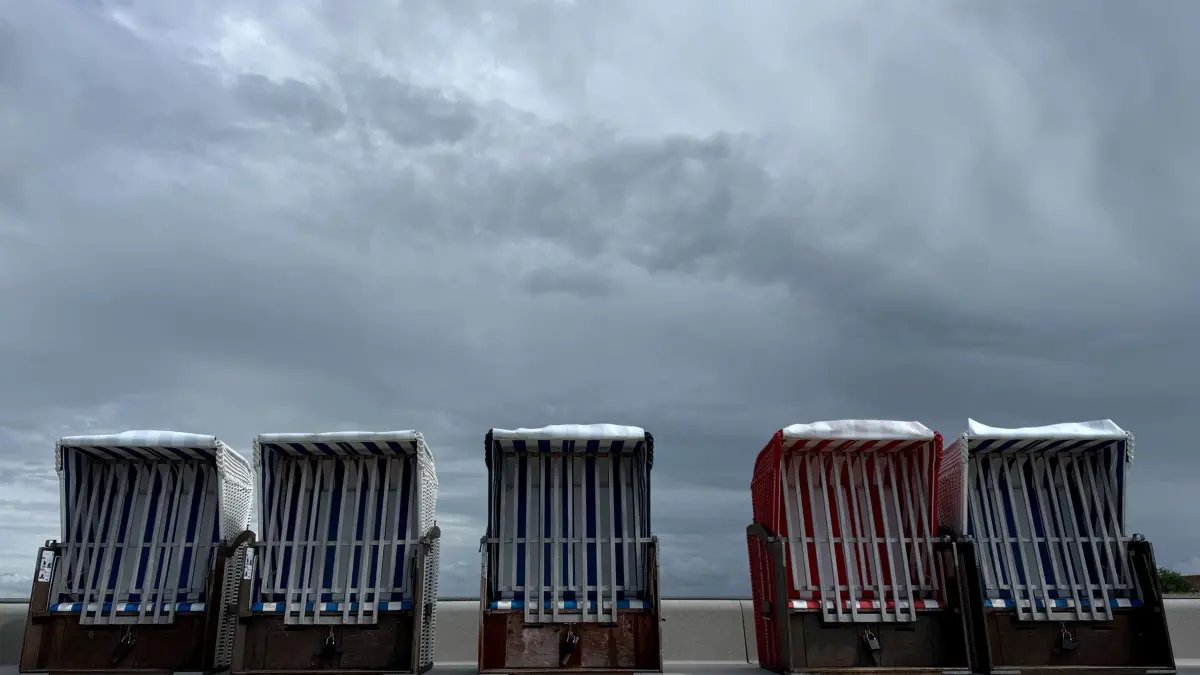 Wechselhaftes Wetter an der Nordsee: ARCHIV - 04.06.2026, Schleswig-Holstein, Friedrichskoog-Spitze: Dunkle Wolken ziehen über den Deich an der Nordsee mit der Promenade und geschlossenen Strandkörben. (zu dpa: «Schauer und Gewitter bringen unbeständiges Wetter im Norden») Foto: Daniel Bockwoldt/dpa +++ dpa-Bildfunk +++
