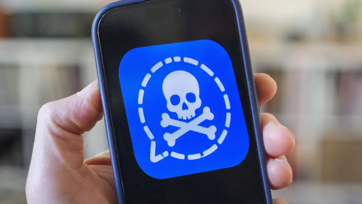 Symbolfoto zur Cyber-Spionage auf Signal: Ein Smartphone zeigt eine manipulierte Version des Messenger-Logos mit Totenkopf-Symbol.