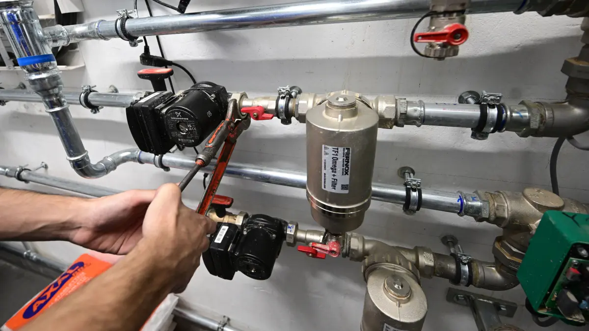 ARCHIV - 05.09.2023, Baden-Württemberg, Plankstadt: Ein Mitarbeiter in einem Handwerksbetrieb für Heizungsbau arbeitet in einem Heizungskeller eines Sportheims an der Installation der Technik für eine Wärmepumpe. (zu dpa: «Neues Heizungsgesetz: Mieterbund warnt vor steigenden Kosten») Foto: Bernd Weißbrod/dpa +++ dpa-Bildfunk +++