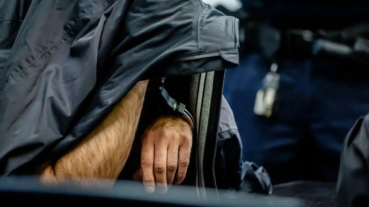 Zwölf Jahre Haft im Prozess um verweste Kofferleiche: 23.07.2025, Baden-Württemberg, Stuttgart: Ein Angeklagter sitzt mit Handschellen für die Urteilsverkündung in einem Saal des Landgerichts Stuttgart und verdeckt sein Gesicht. Der 51-jährige Mann muss für zwölf Jahre ins Gefängnis. Das Landgericht Stuttgart sieht es als erwiesen an, dass der Angeklagte eine 39-jährige Bekannte aus dem Drogenmilieu tötete und ihren Leichnam in Müllsäcke eingewickelt und in einem Koffer ablegte. Foto: Christoph Schmidt/dpa +++ dpa-Bildfunk +++