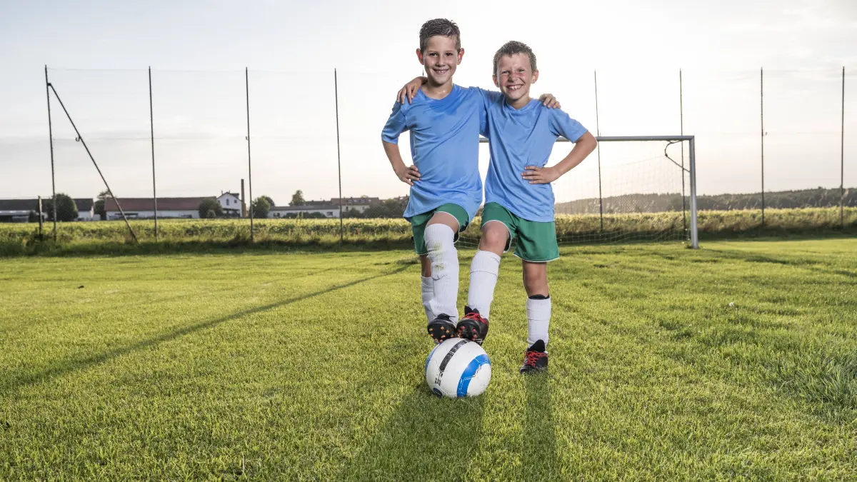Smiling young football players embracing on football ground model released Symbolfoto property released PUBLICATIONxINxGERxSUIxAUTxHUNxONLY WESTF24044