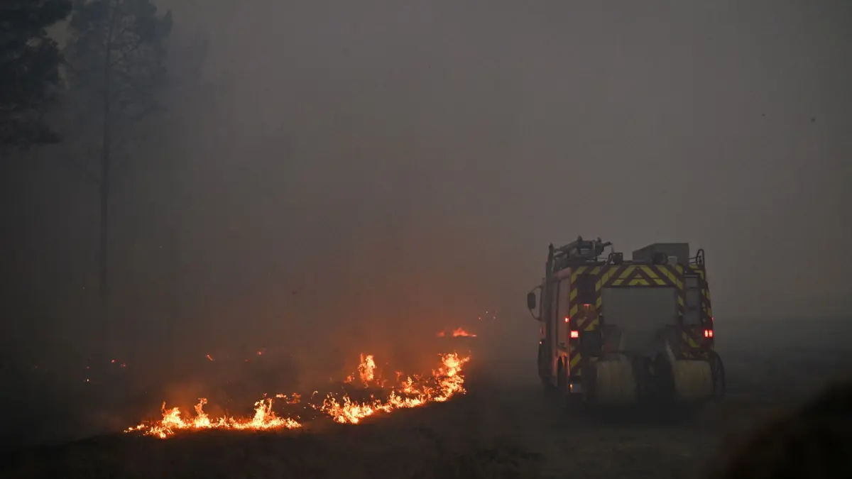 Brände in Frankreich: 26.07.2026, Frankreich, Bordeaux: Ein Löschfahrzeug fährt durch den Rauch eines in der Nähe von Marcheprime, vor den Toren von Bordeaux wütenden Waldbrands. Foto: Emma Da Silva/AP/dpa +++ dpa-Bildfunk +++