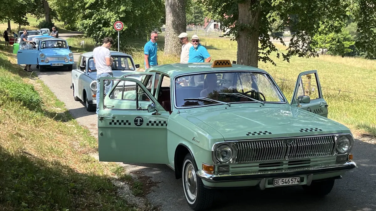 Ein Wolga-Taxi, Baujahr 1972, mit kyrillisch beschriftetem Taxometer führt bei der sommerlichen Ausfahrt eine kleine Trabi-Schlange an.