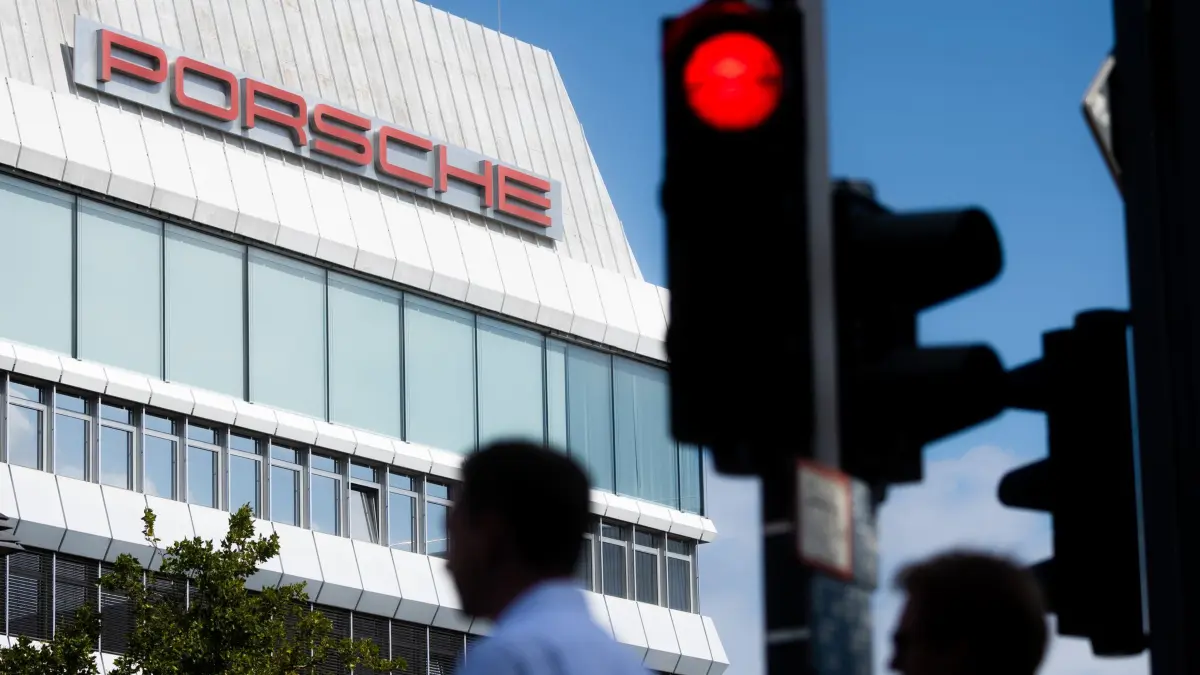Porsche Werk Zuffenhausen: 27.07.2025, Baden-Württemberg, Stuttgart: Während das Porsche Logo auf einem Gebäude am Firmensitz in Stuttgart-Zuffenhausen zu sehen ist, leuchtet davor eine Verkehrsampel Rot. Foto: Christoph Schmidt/dpa +++ dpa-Bildfunk +++