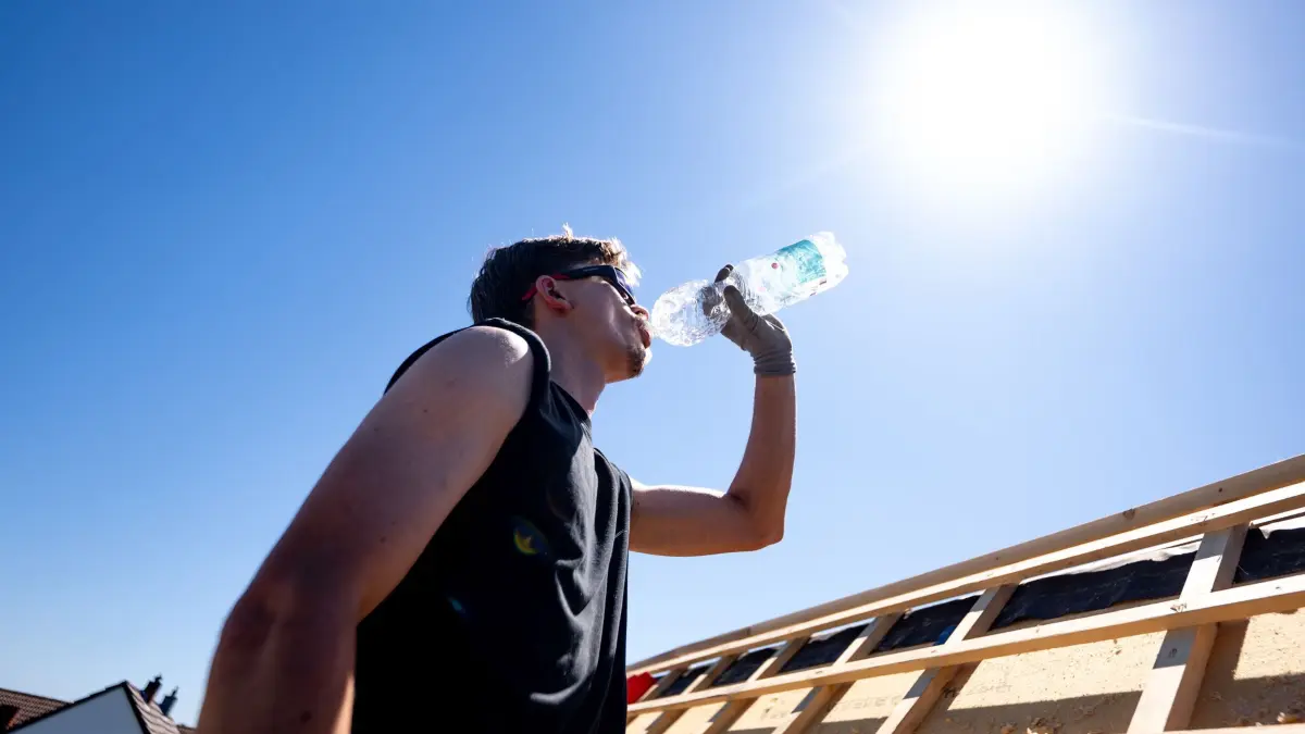 Wetter in Nordrhein-Westfalen: ARCHIV - 26.05.2026, Nordrhein-Westfalen, Sankt Augustin: Ein Dachdecker trinkt Wasser unter der sengenden Sonne bei über 30 Grad auf einem Dach (zu dpa: «Hitzewelle treibt Eis- und Wasserverkauf in Deutschland an») Foto: Benjamin Westhoff/dpa +++ dpa-Bildfunk +++
