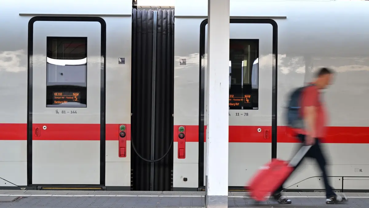 Was sich im August ändert: ARCHIV - 24.06.2026, Bayern, München: Ein Passagier läuft am Morgen, nach dem bundesweiten Ausfall bei der Deutschen Bahn, am Hauptbahnhof München an einem ICE-Zug vorbei. (zu dpa: «Bahn, Ganztag, Solarstrom – was sich im August ändert») Foto: Peter Kneffel/dpa +++ dpa-Bildfunk +++