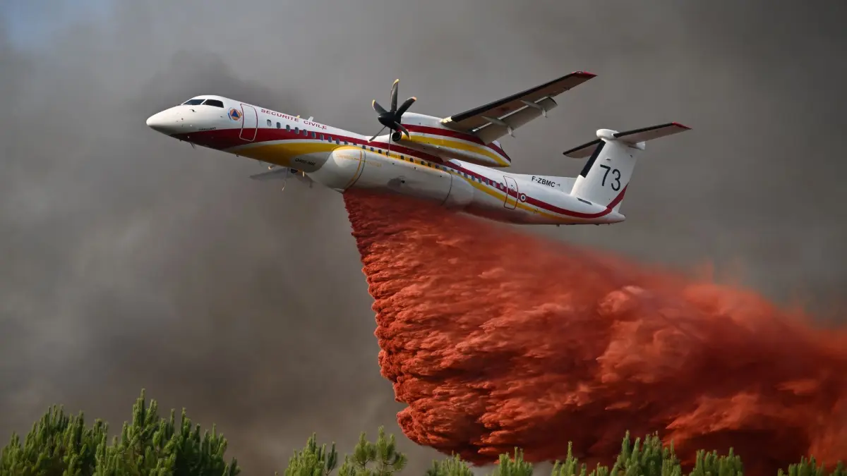 Waldbrände in Frankreich: 29.07.2026, Frankreich, Blagon: Eine De Havilland Canada Dash 8-400 versprüht Löschmittel, während sie bei den Waldbränden im Südwesten Frankreichs über einen Wald fliegt. Foto: Emma Da Silva/AP/dpa +++ dpa-Bildfunk +++