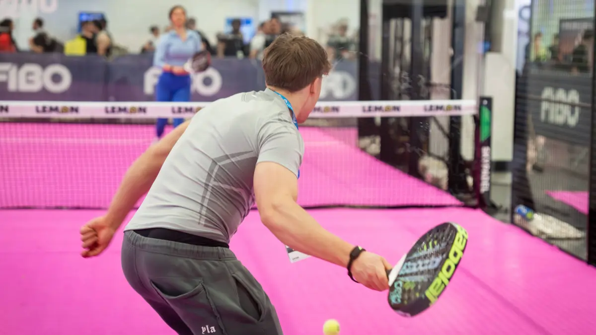 Padel Der Trendsport erobert die Fitnesswelt Symbolbild: Junger Mann schlaegt einen Ball auf einem Padel-Court zurueck. Im Hintergrund das FIBO-Logo. Steht fuer den rasanten Aufstieg von Padel als einer der am schnellsten wachsenden Sportarten Europas. Sinnbild fuer den Trend zu spassbetonten Mannschaftssportarten als Alternative zum klassischen Fitnessstudio sowie fuer die Verbindung von sozialem Miteinander und aktiver Bewegung. Deutschland *** Padel The trend sport conquers the fitness world Symbol image Young man hitting a ball back on a padel court In the background the FIBO logo Stands for the rapid rise of padel as one of the fastest growing sports in Europe Symbolizes the trend towards fun-focused team sports as an alternati