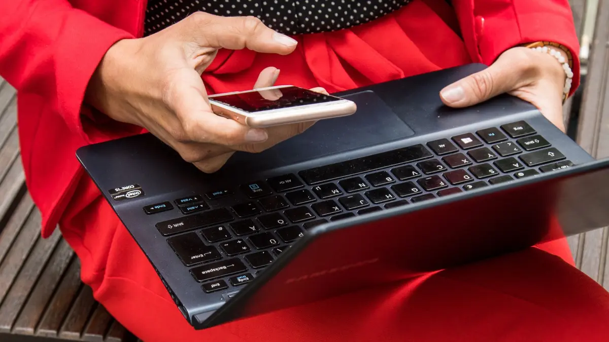 Frau mit Laptop und Smartphone: ILLUSTRATION - Neue Kennzeichnungspflicht für KI-Inhalte ab dem 2. August 2026: Aber nicht jeder muss mitmachen. (zu dpa: «AI-Act: Wer jetzt KI-Generiertes labeln muss - und wer nicht») Foto: Christin Klose/dpa-tmn - Honorarfrei nur für Bezieher des dpa-Themendienstes +++ dpa-Themendienst +++