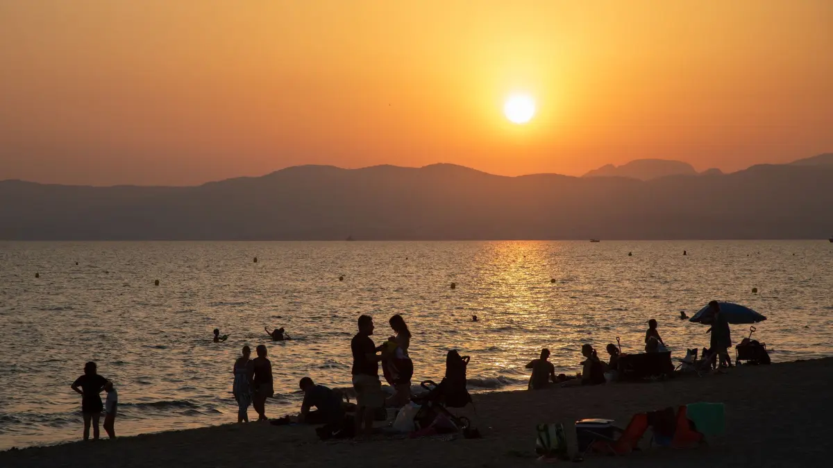 Wetter auf Mallorca am Abend: 29.07.2026, Spanien, Palma: Am Strand von Playa de Palma auf Mallorca baden Menschen bei Sonnenuntergang im Meer. Die hohen Temperaturen locken viele Einheimische und Besucher an, sich bei Sonnenuntergang und in der Nacht am Meer zu erfrischen. Foto: Clara Margais/dpa +++ dpa-Bildfunk +++