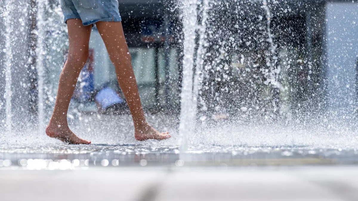 Sommerwetter in Niederbayern: 31.07.2026, Bayern, Straubing: Ein Mädchen erfrischt sich bei sommerlichen Temperaturen an einem Brunnen am Theresienplatz. Foto: Armin Weigel/dpa +++ dpa-Bildfunk +++
