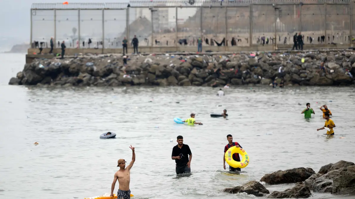 SPAIN-MOROCCO-MIGRATION-CEUTA: Migrants swim through the waters close to the border with Morocco to enter Spain's north Africa's Ceuta enclave on July 31, 2026. Thousands of migrants crossed overnight from Morocco into Ceuta enclave, a police source said, as Spanish Prime Minister was set to arrive to manage the latest migrant crisis on the border. In recent days, a total of around 40,000 migrants have crossed into the territory, population 80,000, the source added. (Photo by JORGE GUERRERO / AFP)