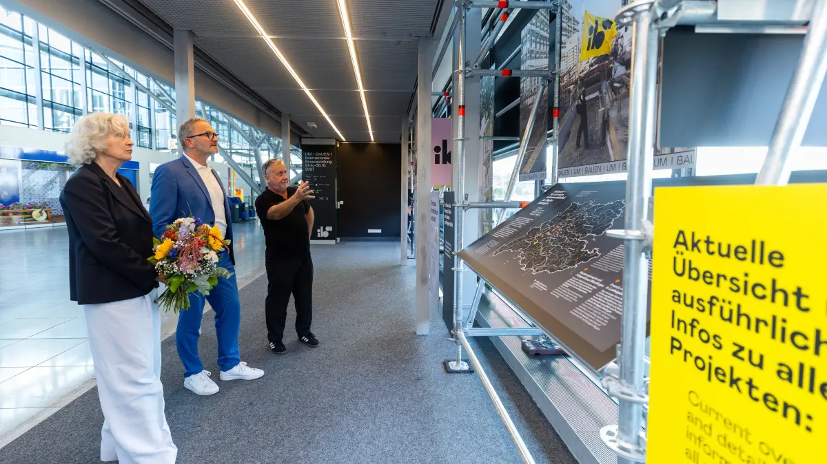 Hans-Peter Künkele (IBA’27-Projektleiter) erläutert dem Geschäftsführer der Flughafen Stuttgart GmbH, Carsten Poralla die Inhalte der IBA’27-Ausstellung, links: Dr. Gabriele König (IBA’27-Geschäftsführerin), (Bild: IBA’27 / Christoph Schmidt)