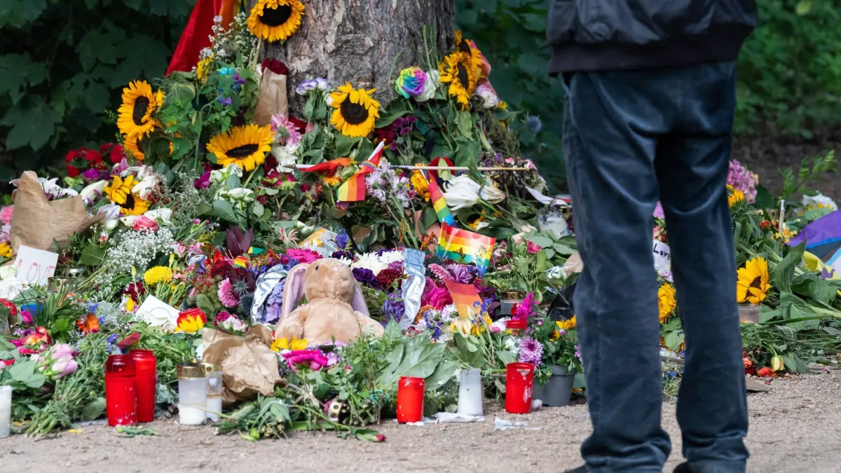 Nach dem Angriff auf CSD in Berlin: ARCHIV - 28.07.2026, Berlin: Trauernde stehen im Tiergarten an einem Baum, an dem unterschiedliche Gegenstände zum Gedenken an die Opfer des Anschlags auf den CSD abgelegt wurden. (zu dpa: «Mahnwache in Berlin für die Opfer des CSD-Anschlags») Foto: Sebastian Christoph Gollnow/dpa +++ dpa-Bildfunk +++