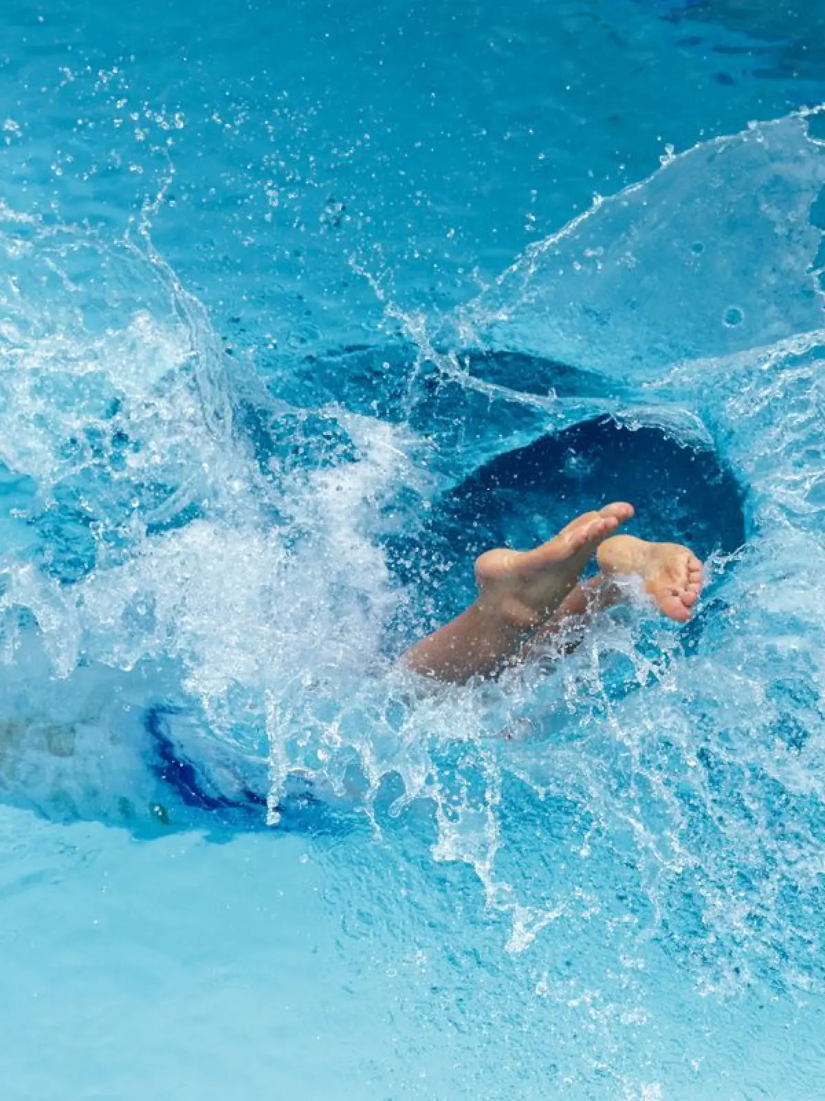 Ein Mann springt in einem Freibad ins Wasserbecken.