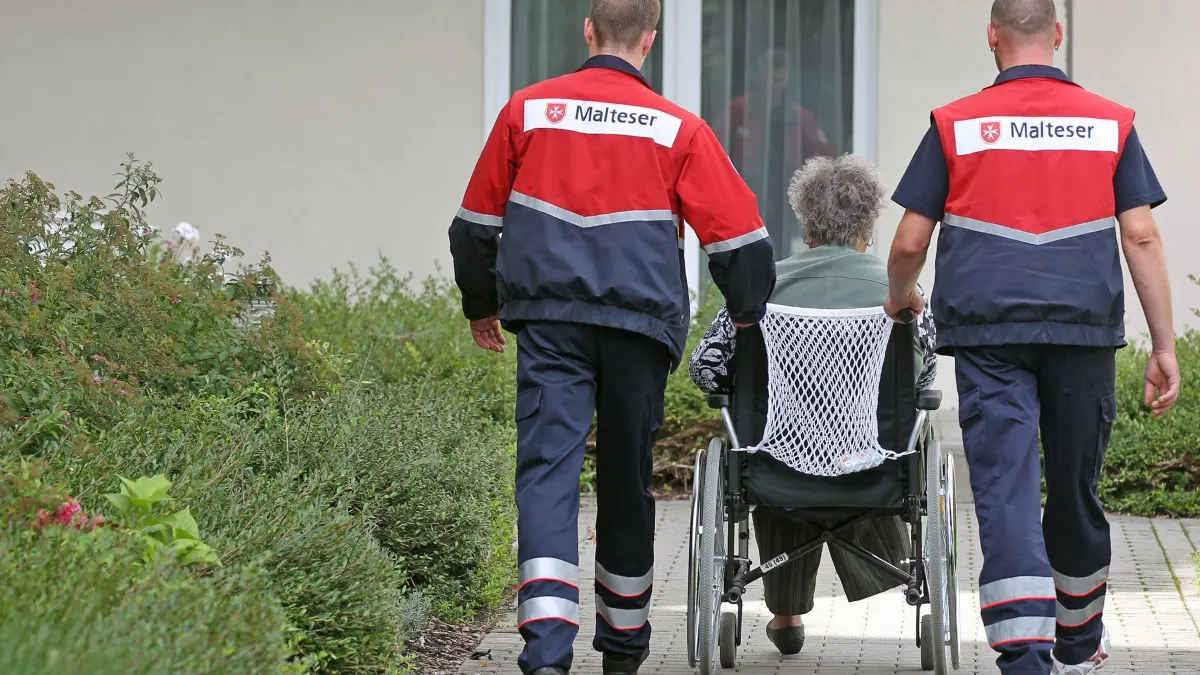 Zivildienst: ARCHIV - 24.08.2010, Sachsen, Leipzig: Zwei Zivildienstleistende der Malteser kümmern sich um eine Dialysepatientin im Rollstuhl. Die Bundesregierung trifft Vorkehrungen für die Einführung eines neuen Zivildienstes für den Fall, dass auch die Wehrpflicht zurückkehren sollte. (Zu dpa "Viele Verbände hätten Interesse an neuem Zivildienst") Foto: Jan Woitas/dpa-Zentralbild/dpa +++ dpa-Bildfunk +++