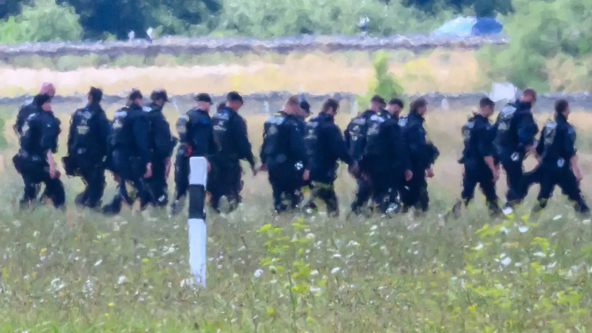 Nach Drohnenvorfall am Flughafen Leipzig/Halle: 06.08.2026, Sachsen, Schkeuditz: Einsatzkräfte der Polizei gehen abseits der Start-und-Lande-Bahn Nord des Flughafens Leipzig/Halle durch das Gelände. Nach dem Drohnenvorfall in der Nacht zum Mittwoch laufen die Ermittlungen. Die für einen Angriff ausgerüstete Drohne war nach Angaben aus Sicherheitskreisen nahe einer ukrainischen Transportmaschine sichergestellt worden. Die Sicherheitsbehörden sind alarmiert. Foto: Hendrik Schmidt/dpa +++ dpa-Bildfunk +++