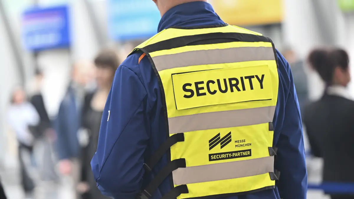 14.03.2025, Bayern, München: Ein Mann mit Security-Weste steht vor Beginn des Treffen der Präsidenten der vier Spitzenverbände der Deutschen Wirtschaft im Eingang der Messehallen. Foto: Peter Kneffel/dpa +++ dpa-Bildfunk +++