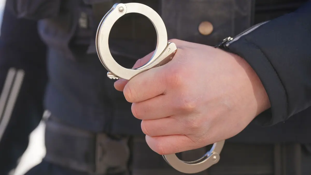 Polizei Handschellen - Symbolbild: ARCHIV - 18.01.2024, Mecklenburg-Vorpommern, Schwerin: Ein Polizist hält Handschellen in der Hand. (zu dpa: «Drei Jahre nach Angriff auf St. Pauli - Verdächtiger in Haft») Foto: Marcus Brandt/dpa +++ dpa-Bildfunk +++