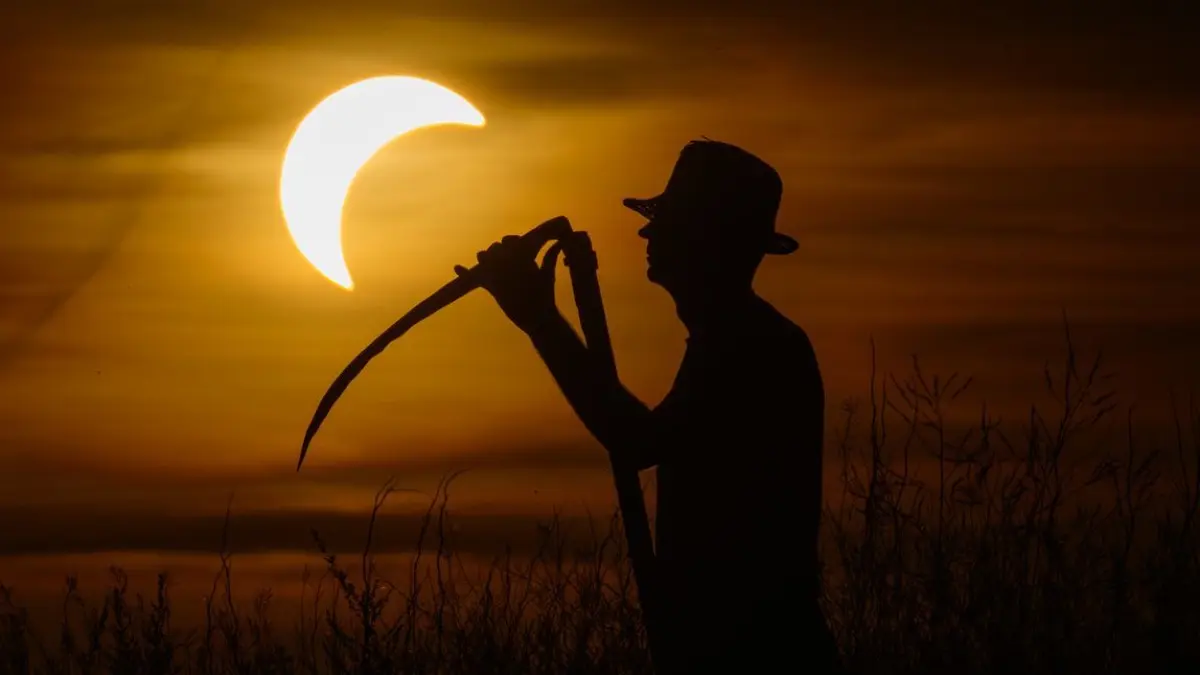 Ein Bauer mit einer Sense steht auf einer Wiese vor der Sonnenfinsternis. Wenn am Abend die partielle Sonnenfinsternis über Deutschland zu sehen ist, herrschen zu dieser Zeit fast überall auch optimale Wetterbedingungen, um sie zu beobachten, hieß es vom Deutschen Wetterdienst.