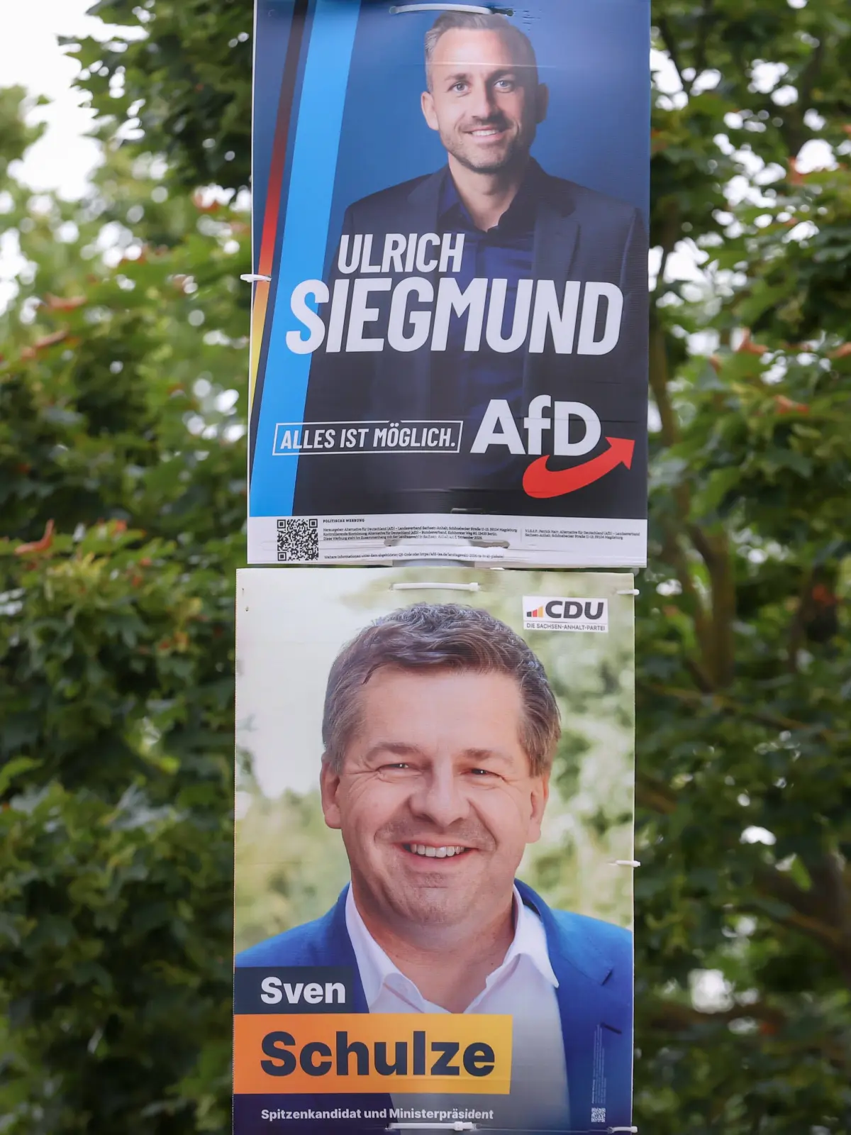 Die Kontrahenten: Wahlplakate von Ulrich Siegmund (AfD), und Sven Schulze (CDU) hängen in Magdeburg gemeinsam an einem Pfosten.