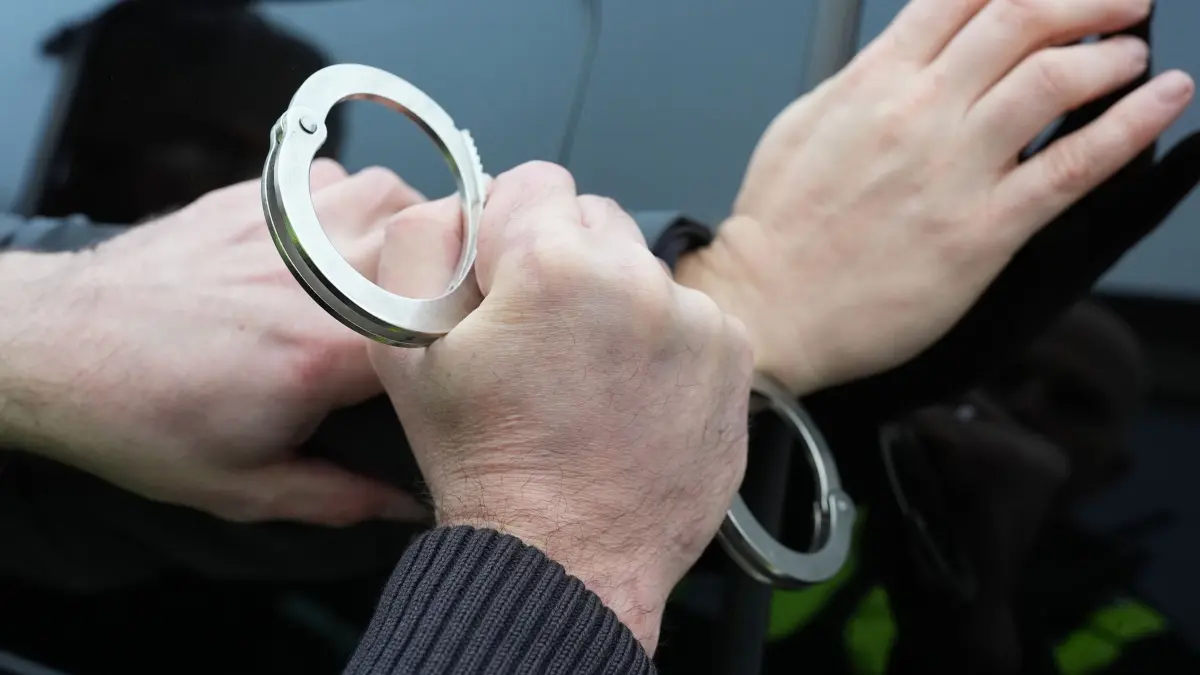 Festnahme Symbolbild: ARCHIV - 11.12.2024, Schleswig-Holstein, Kiel: Ein Polizist legt einem Mann Handschellen an. (Symbolfoto) (zu dpa: «Betrüger gefasst: 68-Jähriger entlarvt falschen Polizisten») Foto: Marcus Brandt/dpa +++ dpa-Bildfunk +++