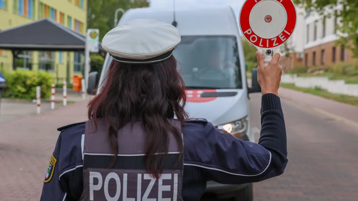 Geschwindigkeits- und Verkehrskontrollen zur Schulwegsicherung: 17.08.2026, Sachsen-Anhalt, Wolmirstedt: Polizeioberkommissarin Verena Freier führt bei polizeilichen Maßnahmen zum Schulbeginn eine Kontrolle mit einer Polizeikelle durch. Die Verkehrssicherheitsaktion "Sicherer Schulweg" bildet den Auftakt der landesweiten Geschwindigkeits- und Verkehrskontrollen zur Schulwegsicherung. Foto: Peter Gercke/dpa +++ dpa-Bildfunk +++