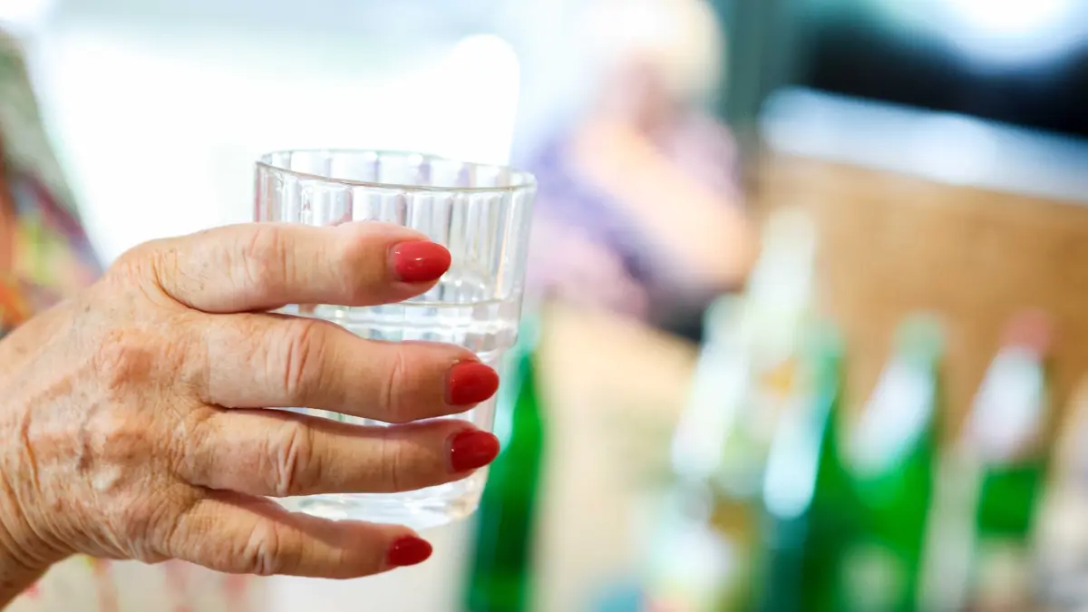 Ältere Menschen leiden unter hohen Temperaturen: ARCHIV - 25.06.2026, Nordrhein-Westfalen, Grefrath: Eine Bewohnerin eines Seniorenheims hält bei sommerlichen Temperaturen ein Glas mit Wasser in ihrer Hand. (zu dpa: «Schon fast 2.900 Hitzetote in NRW») Foto: Christoph Reichwein/dpa +++ dpa-Bildfunk +++