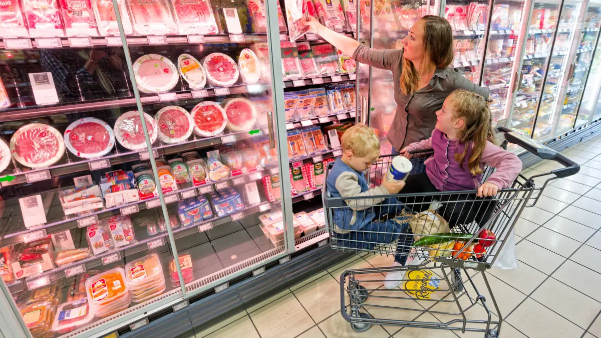 Die Qual der Wahl. Die Mutter mit ihren beiden Kindern bei der abgepackten Wurst im Supermarkt. Traunstein Bayern Deutschland *** Spoiled for Choice: A mother with her two children looking at packaged sausage at a supermarket in Traunstein, Bavaria, Germany Copyright: xRolfxPossx