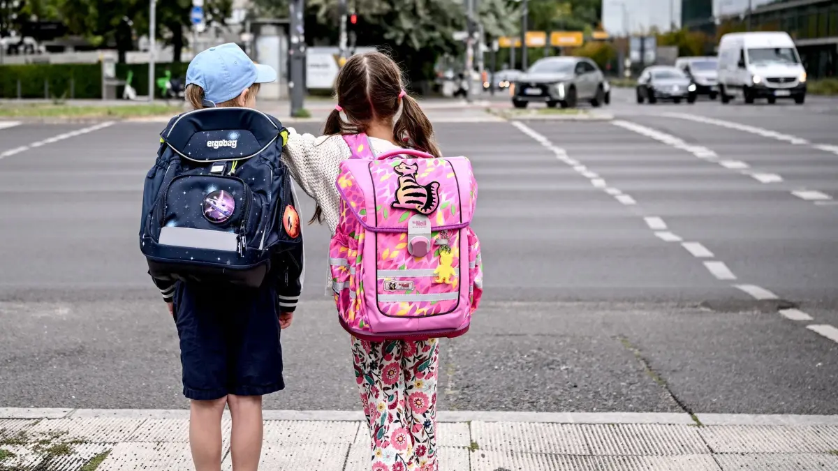 Erster Schultag in Berlin und Brandenburg: 24.08.2026, Berlin: Die Schulanfänger Edgar (6) und Angelina (5) stehen an einer Straße am Rande der Schulanfangskampagne „Achtung Schulweg! Sicher starten, sicher ankommen“. Die Kampagne macht auf die besondere Situation von Kindern im Straßenverkehr aufmerksam und wirbt für mehr Rücksicht und Aufmerksamkeit. Foto: Britta Pedersen/dpa +++ dpa-Bildfunk +++