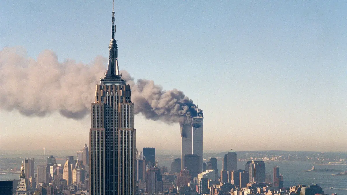 Anschläge vom 11. September 2001: ARCHIV - 11.09.2001, USA, New York: Die Zwillingstürme des World Trade Centers brennen hinter dem Empire State Building. Fast 3.000 Menschen kamen durch die verheerenden Attacken vor 25 Jahren ums Leben. (zu dpa: «Prozess gegen 9/11-Drahtzieher für 2028 geplant») Foto: Marty Lederhandler/AP/dpa +++ dpa-Bildfunk +++