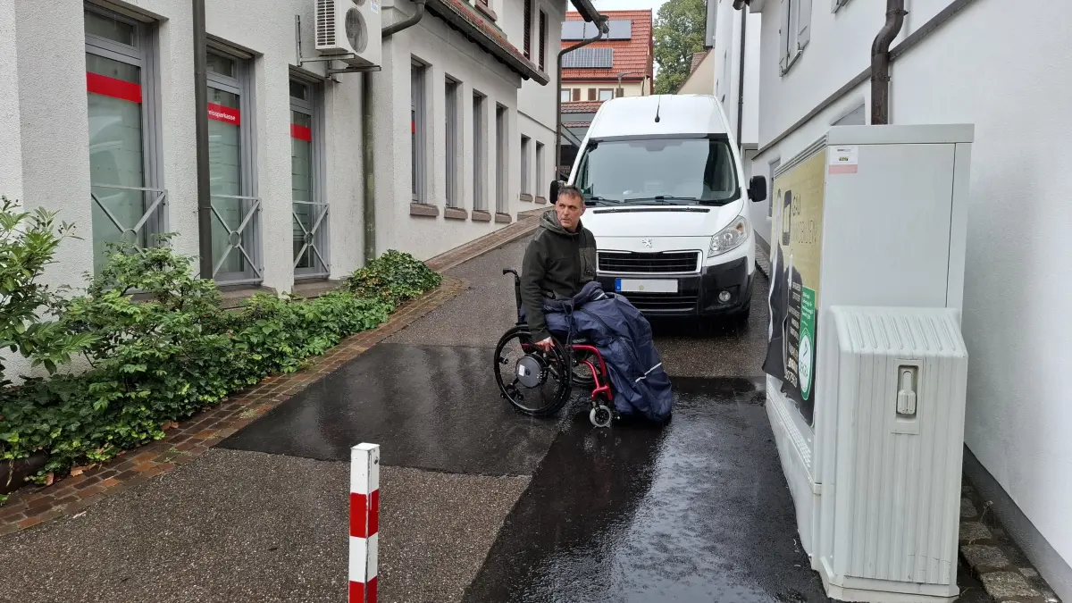 Sven Pannier in Rathausgässle Leonberg Höfingen, mit Rollstuhl. Transporter parkt in der Feuergasse.