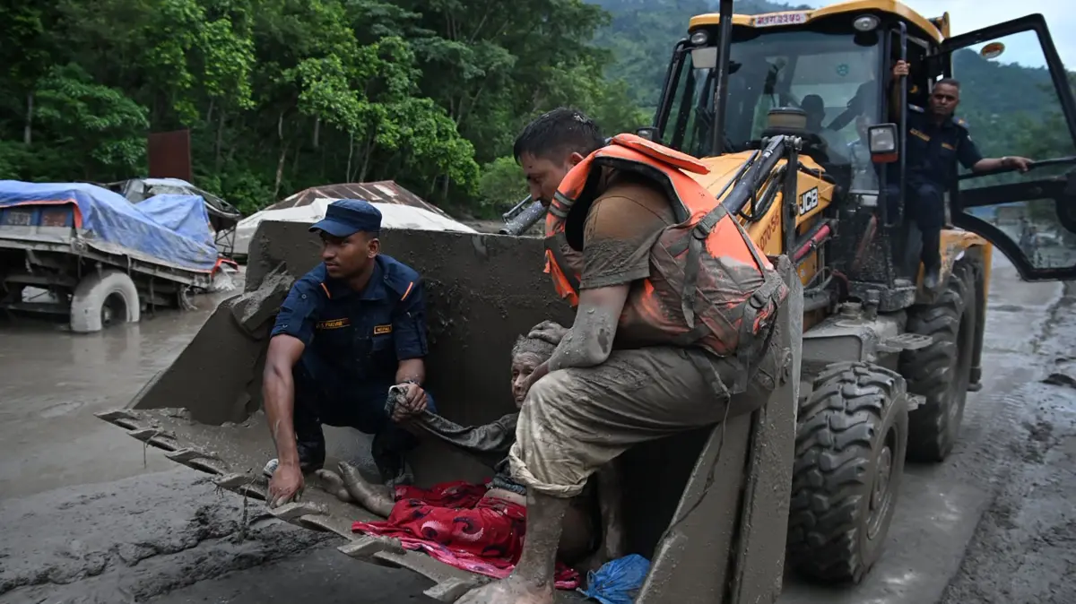 NEPAL-WEATHER-FLOOD: Rescue personnel use an excavator to carry a person affected by flash floods at Devghat in Nepal's Nuwakot district on August 26, 2026. Massive flooding killed eight people in Nepal on August 26, as Chinese state media reported "major casualties" from a mudslide at a Tibet trade hub on China's side of the nations' shared border. (Photo by Prakash MATHEMA / AFP)