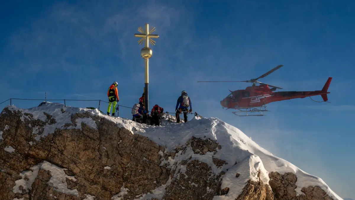 Rücktransport des Zugspitz-Gipfelkreuzes: ARCHIV - 28.11.2025, Bayern, Garmisch-Partenkirchen: Das renovierte Gipfelkreuz steht nach seinem Transport per Helikopter wieder auf der Zugspitze und wird in seiner Vorrichtung montiert. Zuvor wurde es von Aufklebern befreit, restauriert und neu vergoldet. (zu dpa: «Wieder Sticker am Kreuz der Zugspitze: Klebesünder gesucht») Foto: Peter Kneffel/dpa +++ dpa-Bildfunk +++