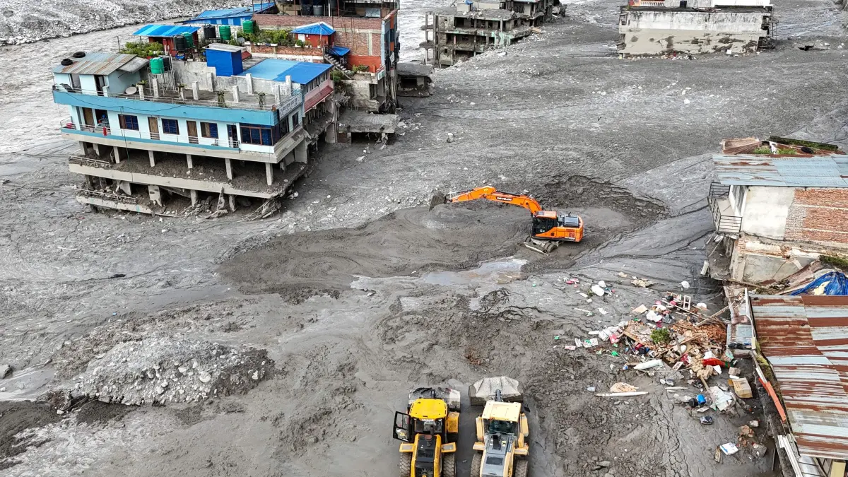 NEPAL-WEATHER-LANDSLIDE-FLOODS: An aerial view shows workers using excavators to clear sludge following flash floods at Trishuli in Nepal's Nuwakot district on August 27, 2026. Rescue teams scoured devastated zones August 27 for more than 1,300 people missing a day after flash floods and landslides along the Nepal-Tibet border killed at least 273, sweeping away entire villages. (Photo by Arun SANKAR / AFP)